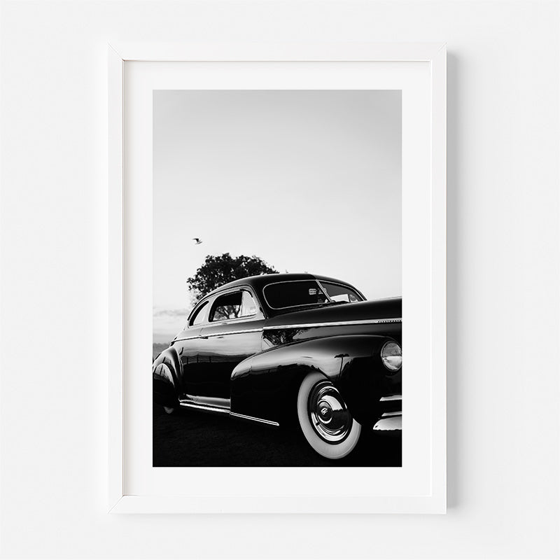 Framed black and white photograph of a classic car on a white background