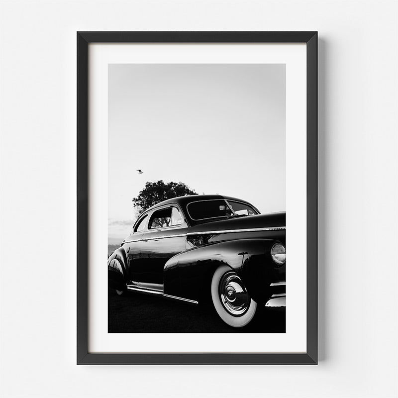 Framed black and white photograph of a classic car on a white background