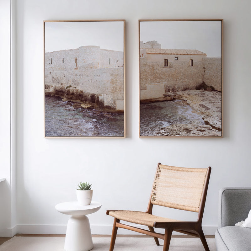Two framed artworks on a wall above a chair and small table.
