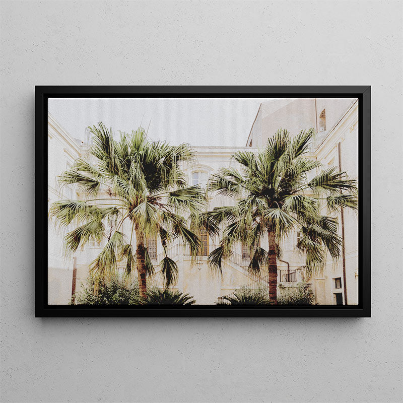 Framed artwork of palm trees in front of a building on a gray wall