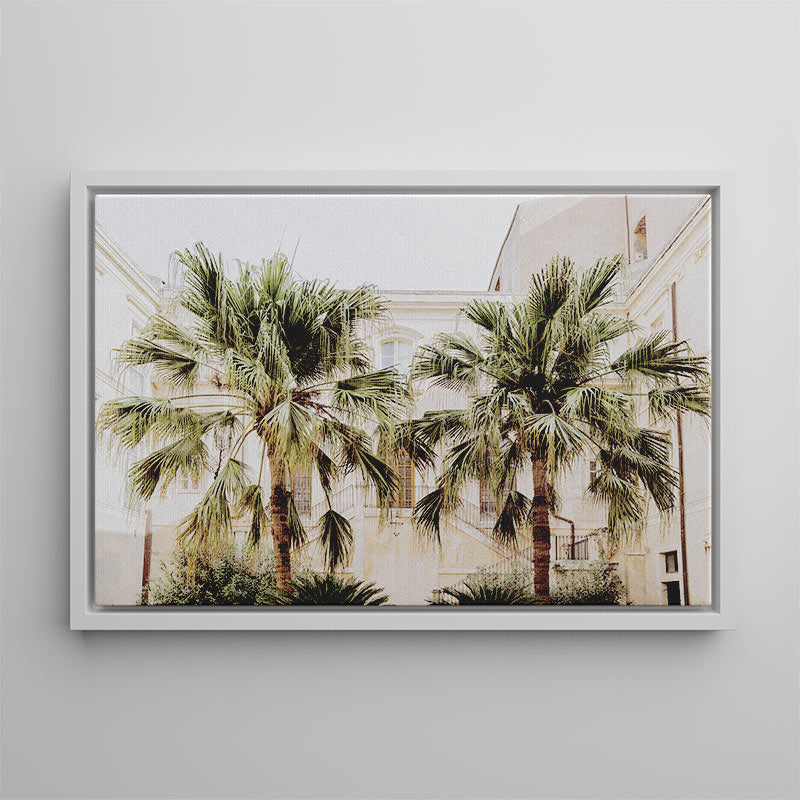 Framed artwork of palm trees in front of a building on a gray wall