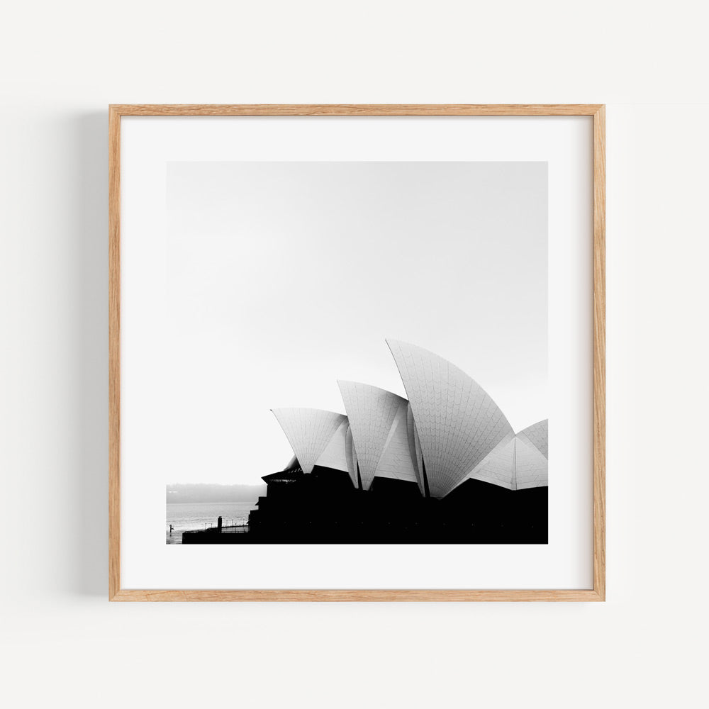 Striking black and white framed view of the Sydney Opera House against the sea, evoking the beauty of Australia's coastline.