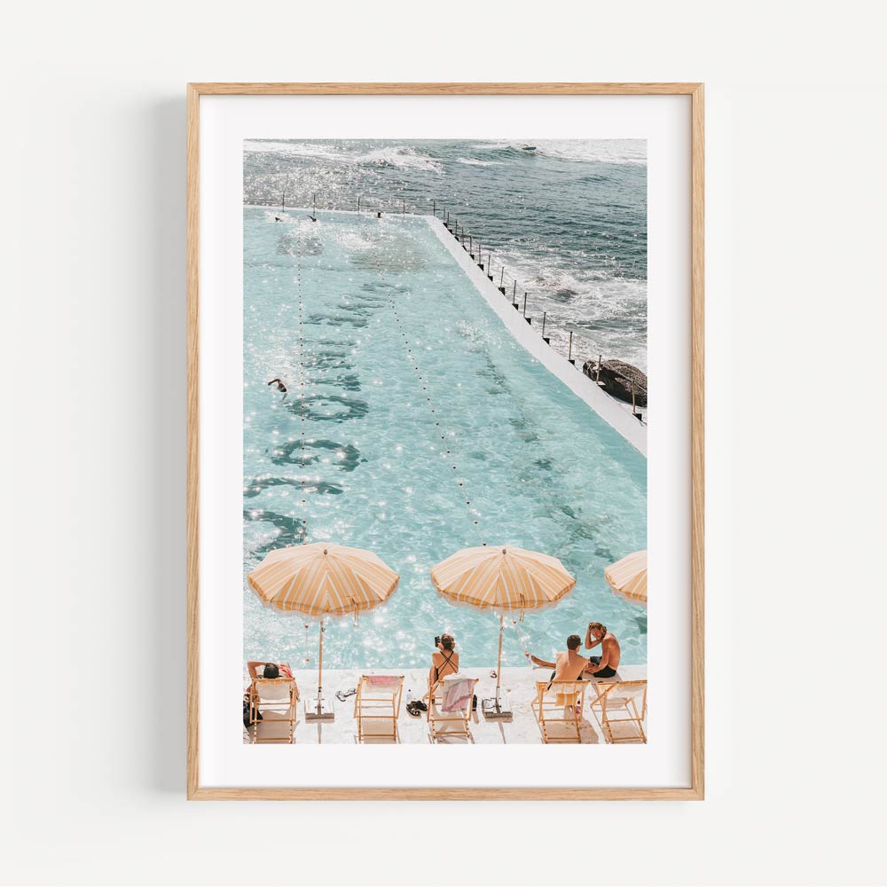 Bondi Icebergs framed art featuring turquoise tones, sunny elegance, and a festive poolside scene.