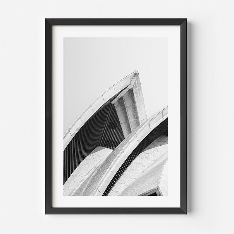 Framed black and white architectural print of a modern building on a white wall.