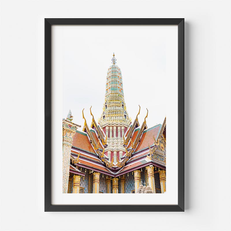 A framed art print of the Grand Palace spire in Bangkok, featuring a black frame and white matting, shown against a light gray wall.