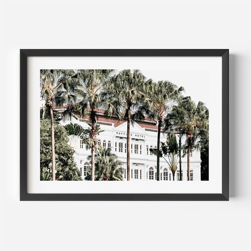 Framed photograph of a hotel with palm trees on a white wall