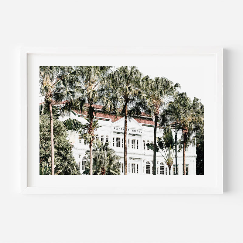 Framed photograph of a white building with palm trees in front on a white background