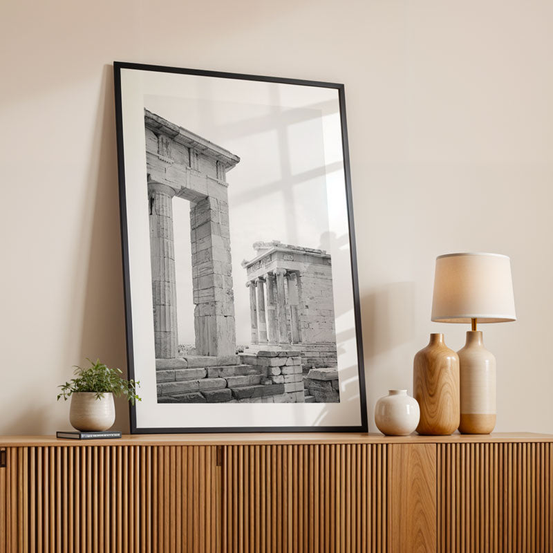 Framed black and white print of ancient architecture on a wooden console table with decorative items.