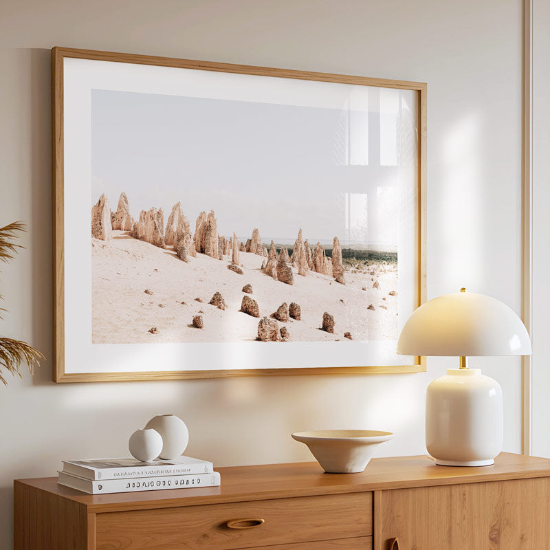 Framed landscape print on a wall above a wooden console table with decorative items.