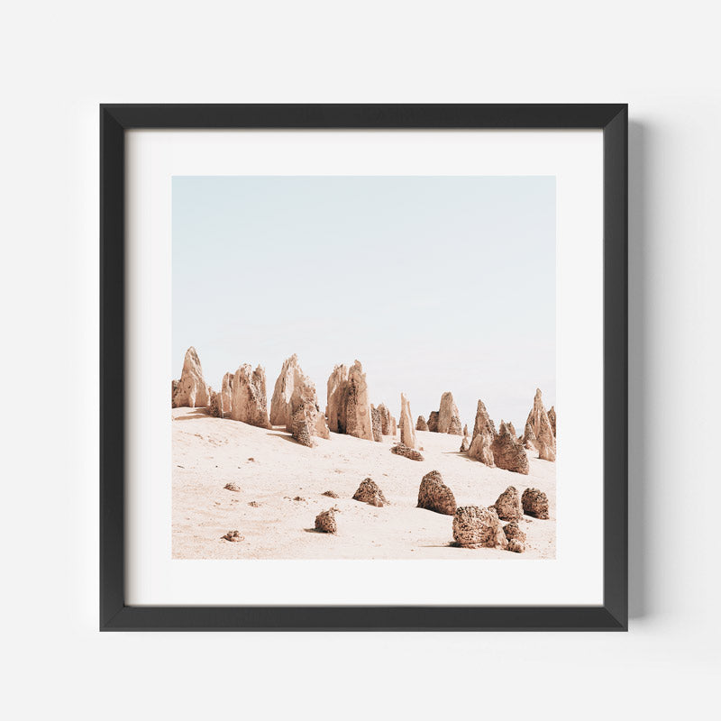 Framed artwork of desert landscape with rock formations on a white wall