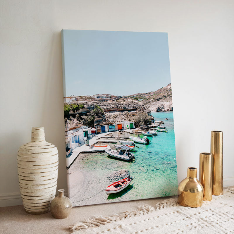 Canvas print of a coastal scene with boats and buildings, displayed on a wall with decorative vases.