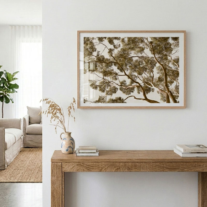 Framed tree artwork on a wall above a wooden console table in a living room.