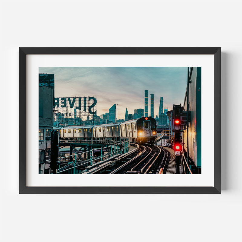 Framed photograph of a train on tracks with city skyline in the background