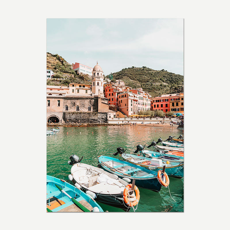Harbor scene with boats and colorful buildings on a hillside.