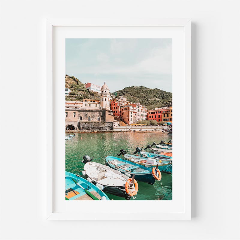 Framed photograph of a coastal scene with boats and colorful buildings.