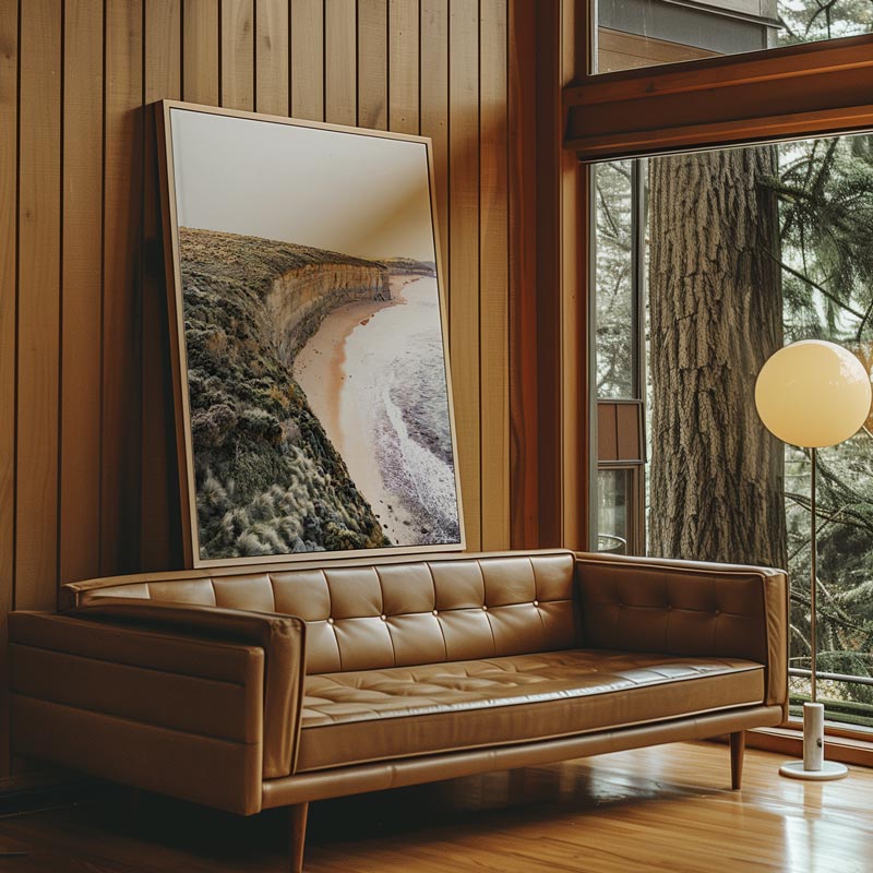 Brown leather sofa in a room with wooden walls and a large window showing trees.