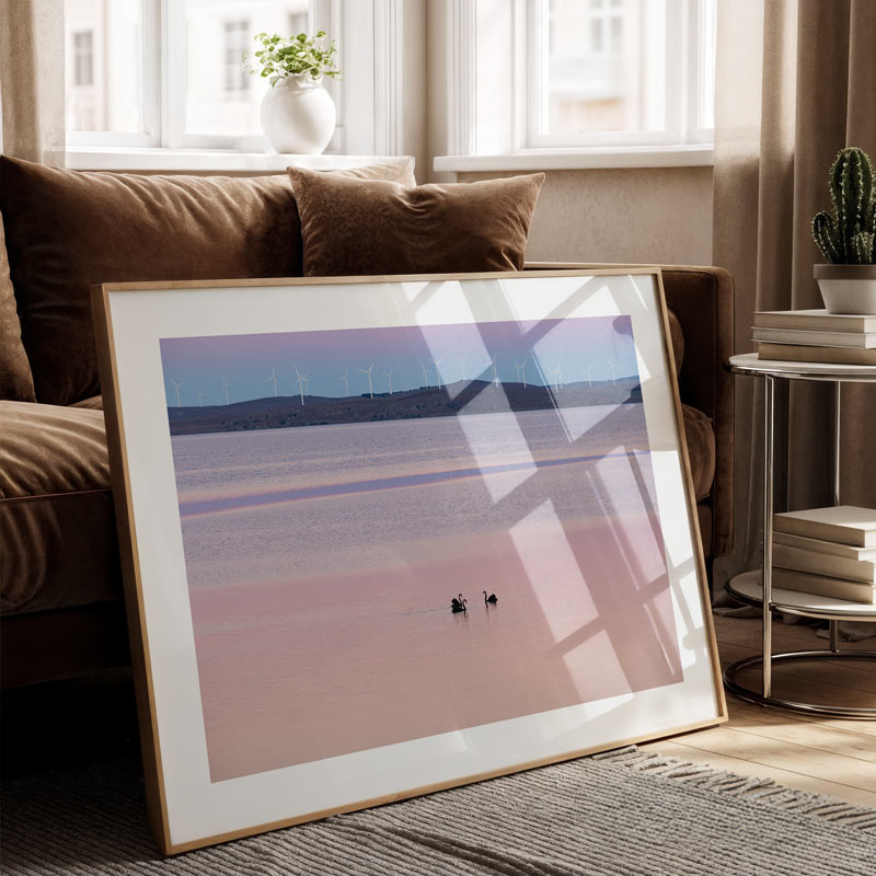 Framed artwork of a landscape with two figures on a beach in a living room.
