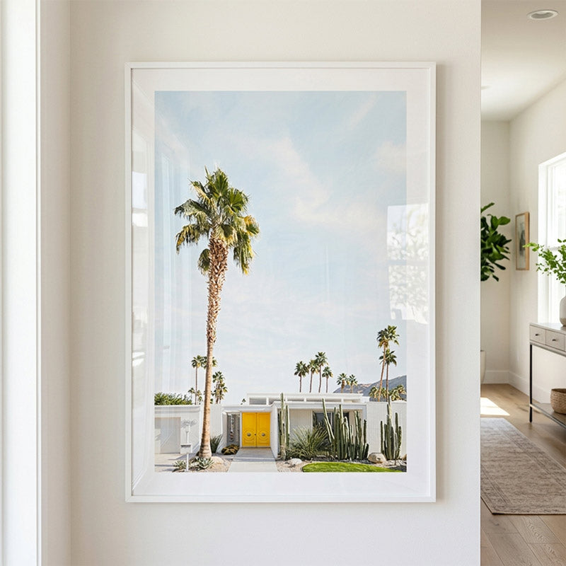 Framed artwork of a palm tree and house scene in a modern interior setting.