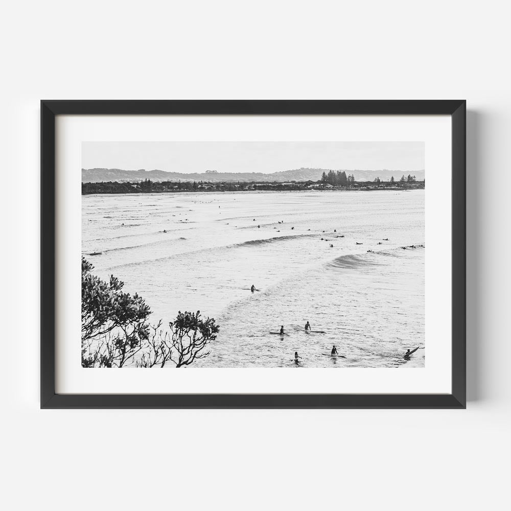A mesmerizing black and white image of surfers at The Pass, Byron Bay - perfect for your wall decor needs.