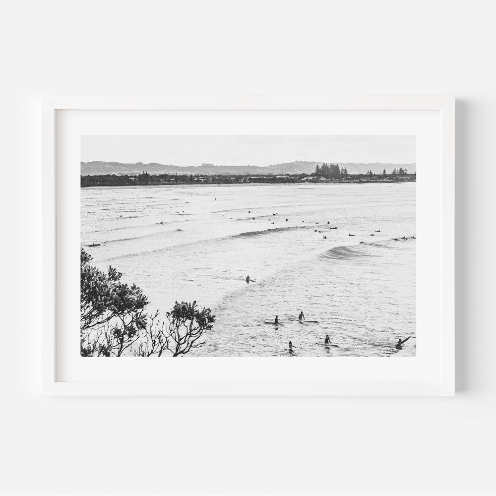 Black and white photo of surfers at The Pass, Byron Bay - a stunning wall art for your home or office decor.