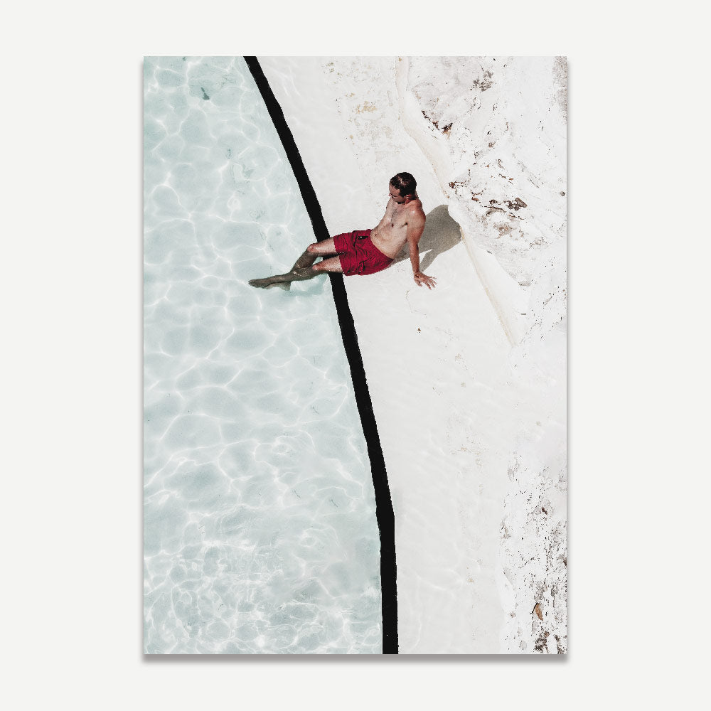 The print of a man in red shorts sitting on the edge of Bondi Icebergs Pool