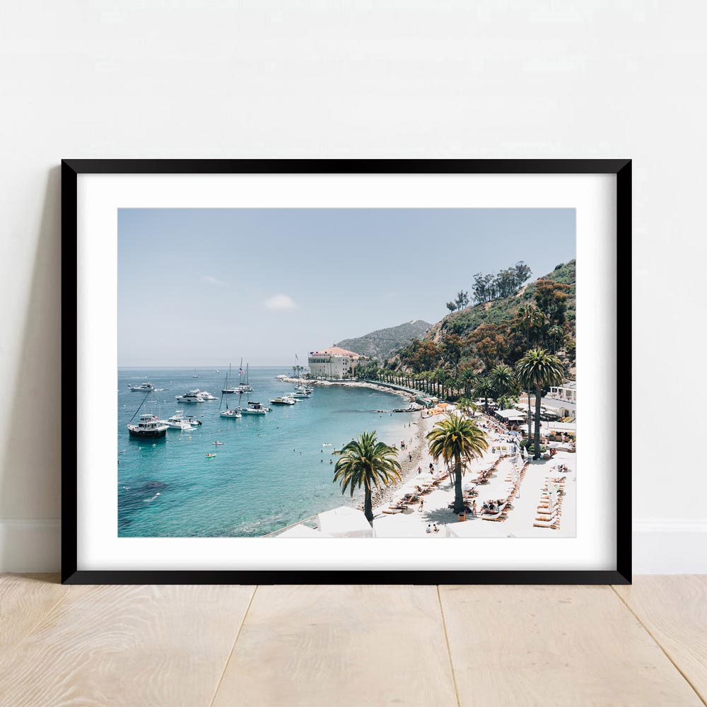 Stunning wall art decor with a white framed photo of a beach, boats, and palm trees. Real photography from Santa Catalina Island, California by Oblongshop.
