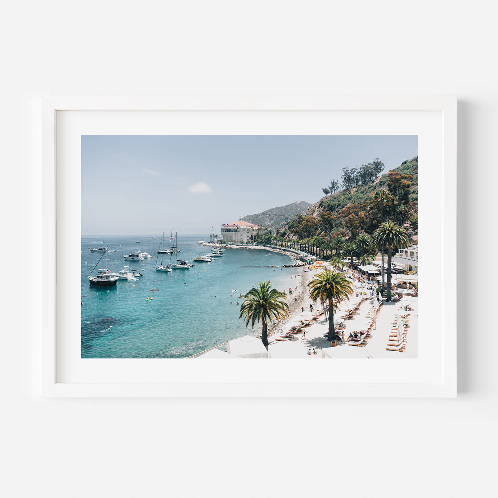 A white framed photo of a beach with boats and palm trees, perfect for wall art decor from Oblongshop. Real photography of Santa Catalina Island, California.