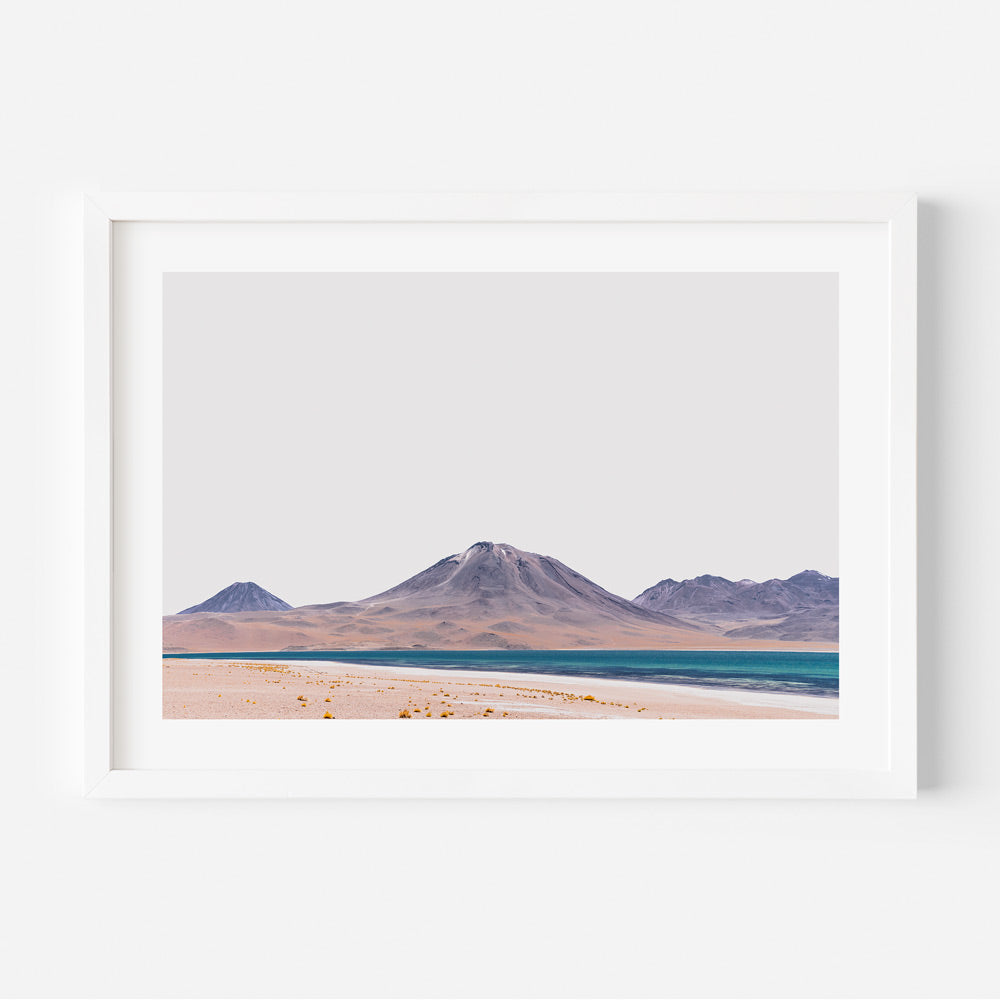 A framed print featuring a landscape with mountains and a clear sky, predominantly in shades of blue, orange, and white.