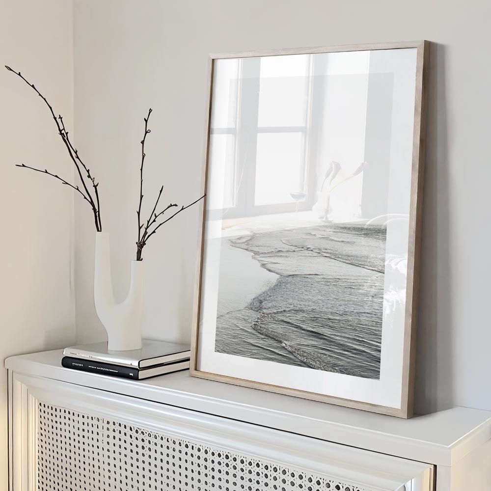 Wall art featuring a white framed photo of the ocean waves at Huntington Beach, California.