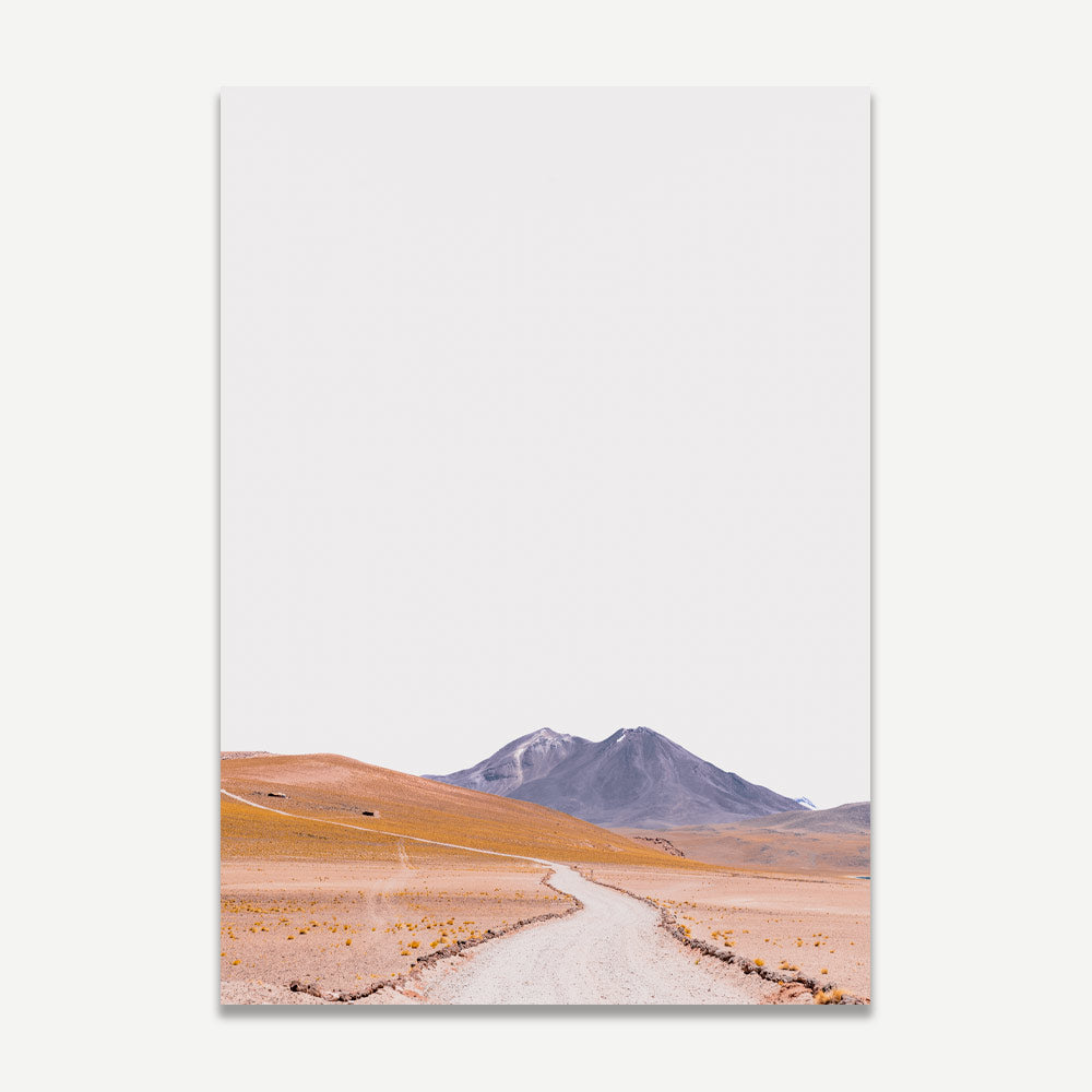 A landscape photograph featuring a dirt road leading towards a volcano in the Atacama region of Chile.