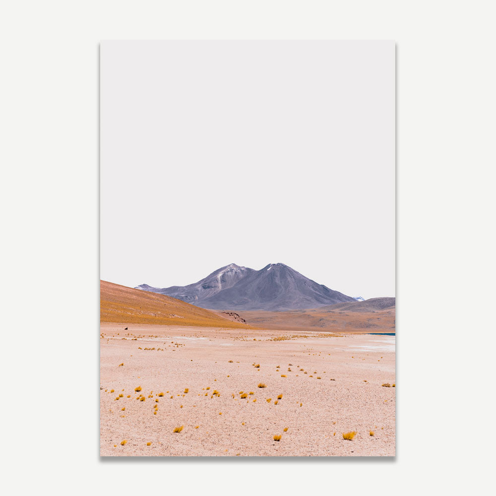 A landscape photograph featuring a desert plain with mountains in the background, predominantly in shades of blue and orange.