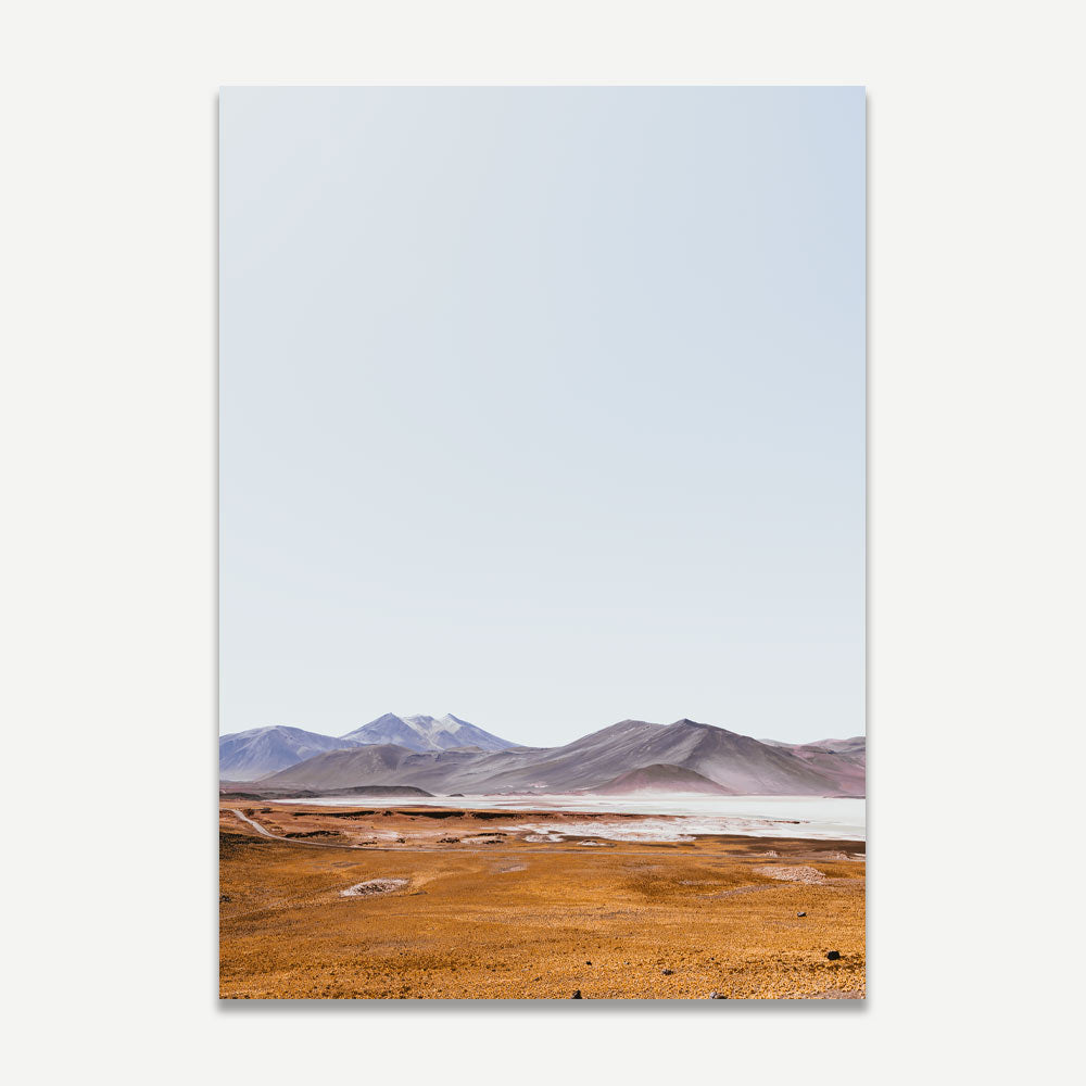 A landscape photograph featuring a desert scene with mountains in the background, predominantly orange and blue colors.