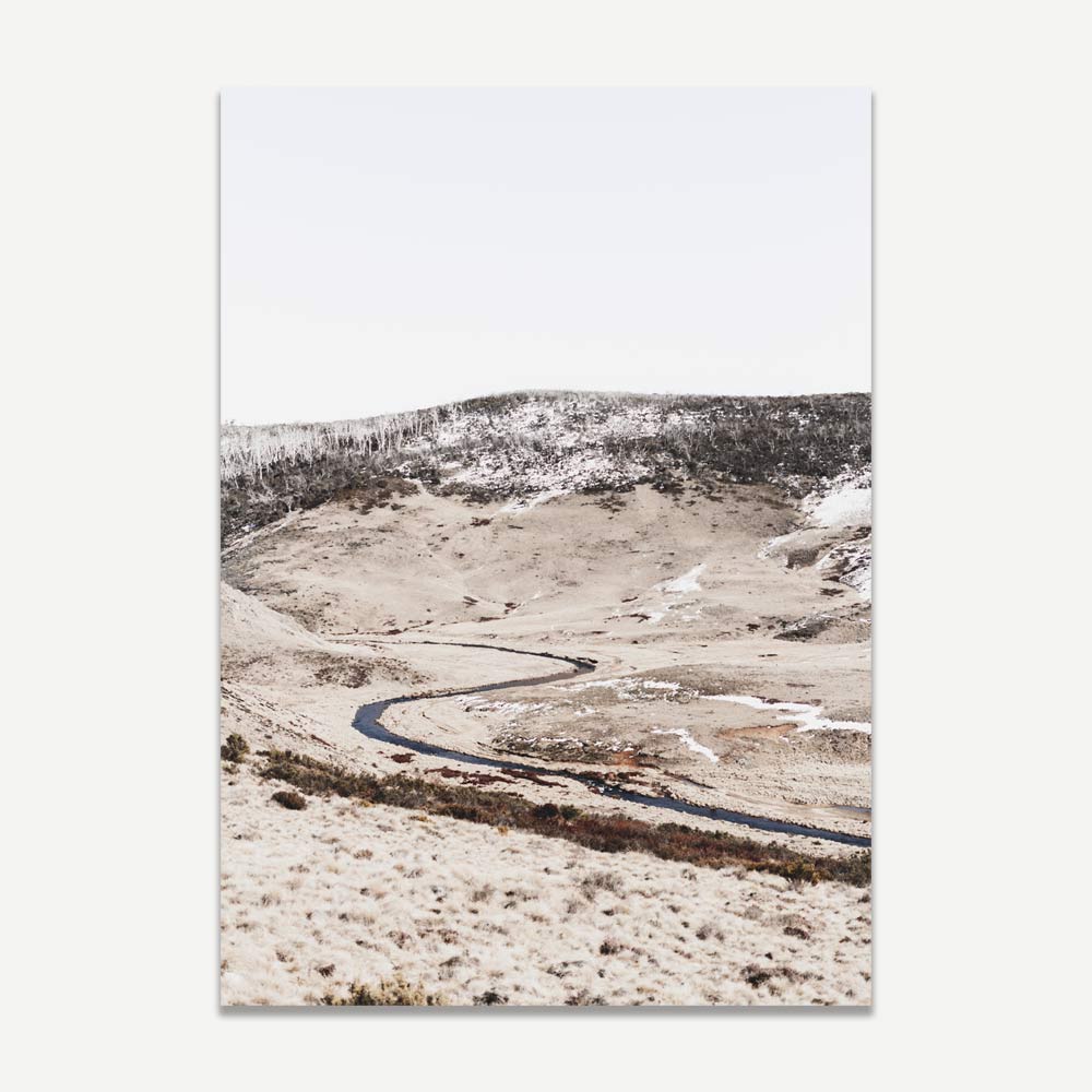 A landscape photograph of Snowy Mountains in Australia with a winding road and snow-covered ground.
