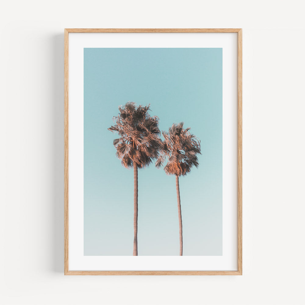 Sunny California Skyline: Framed canvas print of twin palm trees silhouetted against a vibrant blue sky, adding coastal charm to any room.